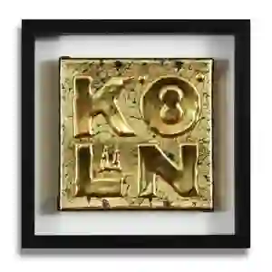 Motiv mit Köln Schriftzug als Applikation unter Blattgold (Imitat), auf 18 x 18 cm großer Leinwand, in einem schwarzen Rahmen.